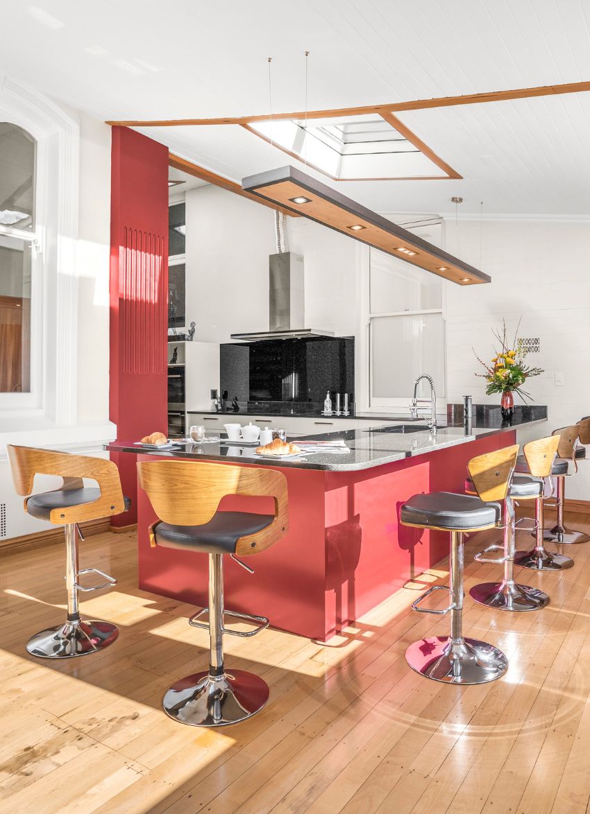 Wide kitchen view with bold Resene Hot Wired peninsula and restored rimu floors