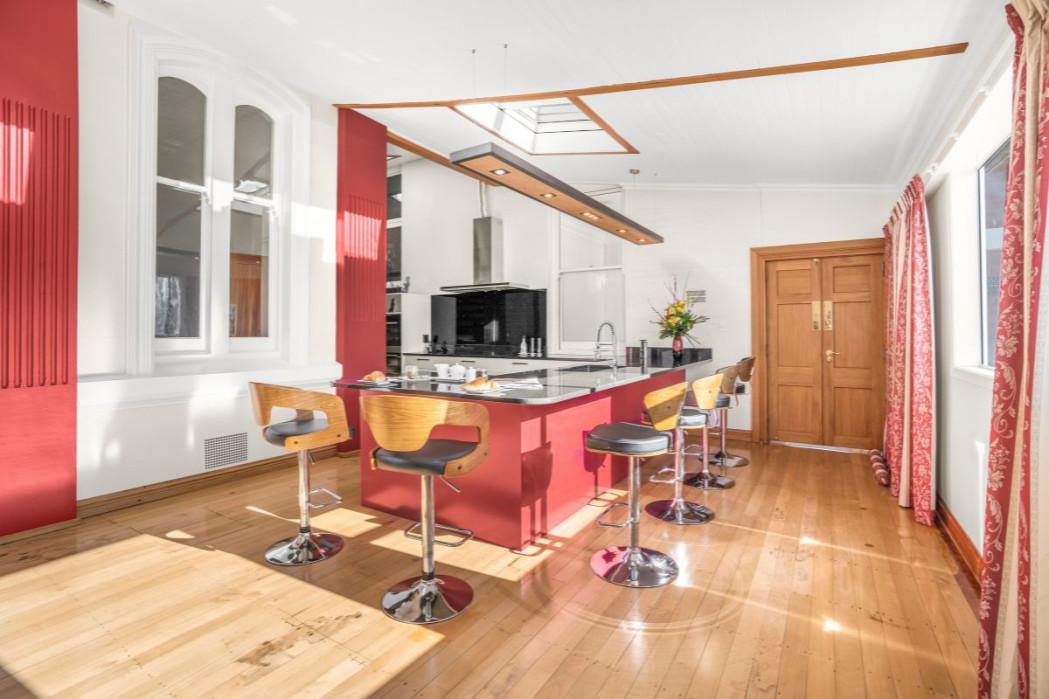 Wide kitchen view with bold Resene Hot Wired peninsula and restored rimu floors